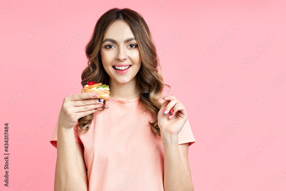 Pretty smiling young woman with a delicious pastry cake on pink background Pretty smiling young woman with a delicious pastry cake on pink background