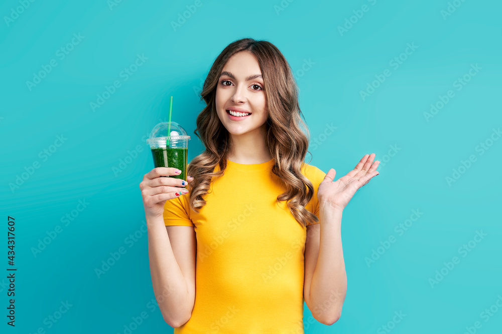 Pretty happy woman with tasty green detox juice on blue background Pretty happy woman with tasty green detox juice on blue background