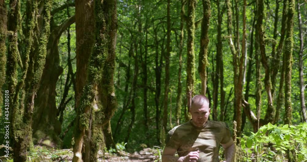 handsome brutal man sportsman jogging in the forest in special khaki clothes. handsome brutal man sportsman jogging in the forest in special khaki clothes.