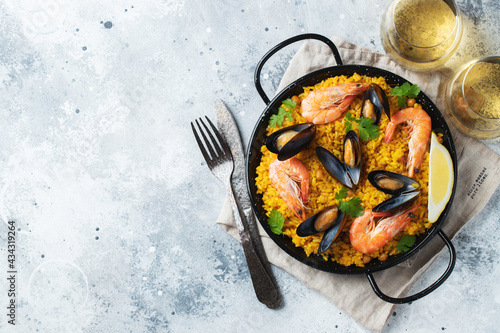 Obraz na plátně Traditional spanish seafood paella in pan with chickpeas, shrimps, mussels, squid on light grey concrete background