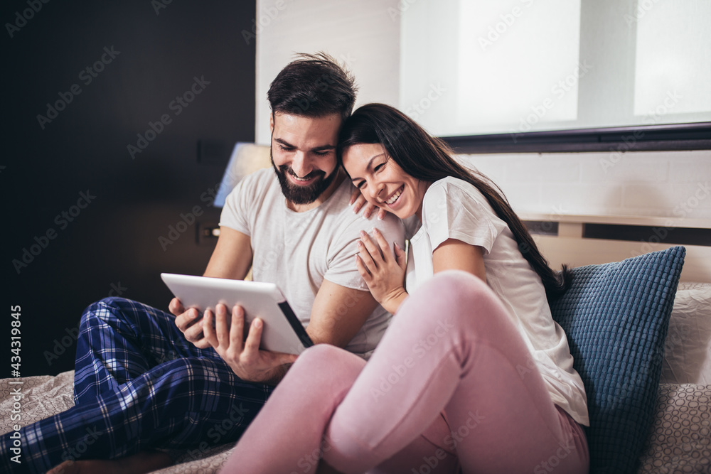 Young couple using tablet in a hotel room while lying on the bed. Young couple using tablet in a hotel room while lying on the bed.