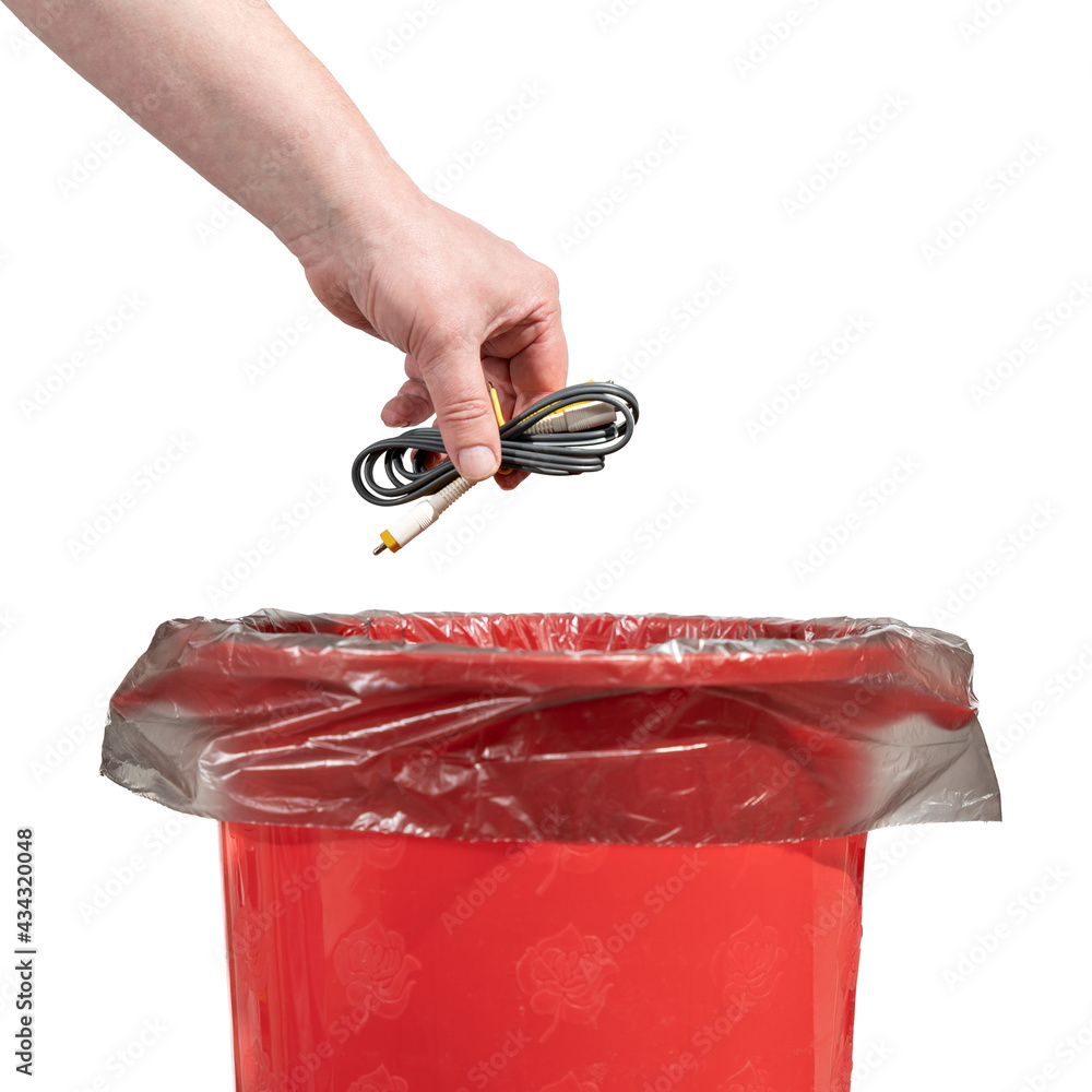 A man tosses a bundle of obsolete wires into a trash can. Male hand