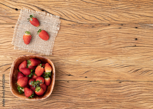 Strawberries in a bowl over wooden table with copy space