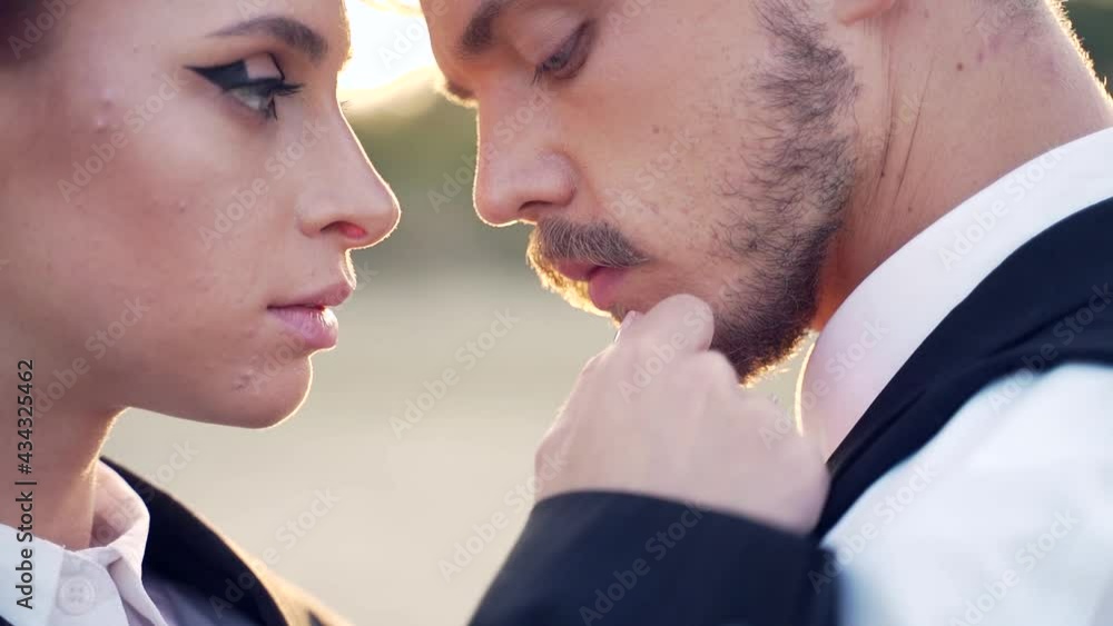 Close-up portrait of a passionate couple in love looking at each other background of sunset outside. Young stylish man and woman in suit hugging close up. Bearded male and redheaded female outdoors Close-up portrait of a passionate couple in love looking at each other background of sunset outside. Young stylish man and woman in suit hugging close up. Bearded male and redheaded female outdoors