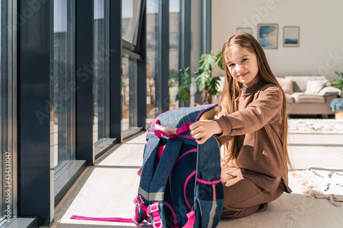 Little girl prepares school backpack