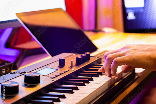 Wall Mural male musician hand playing midi keyboard for arranging music on laptop computer