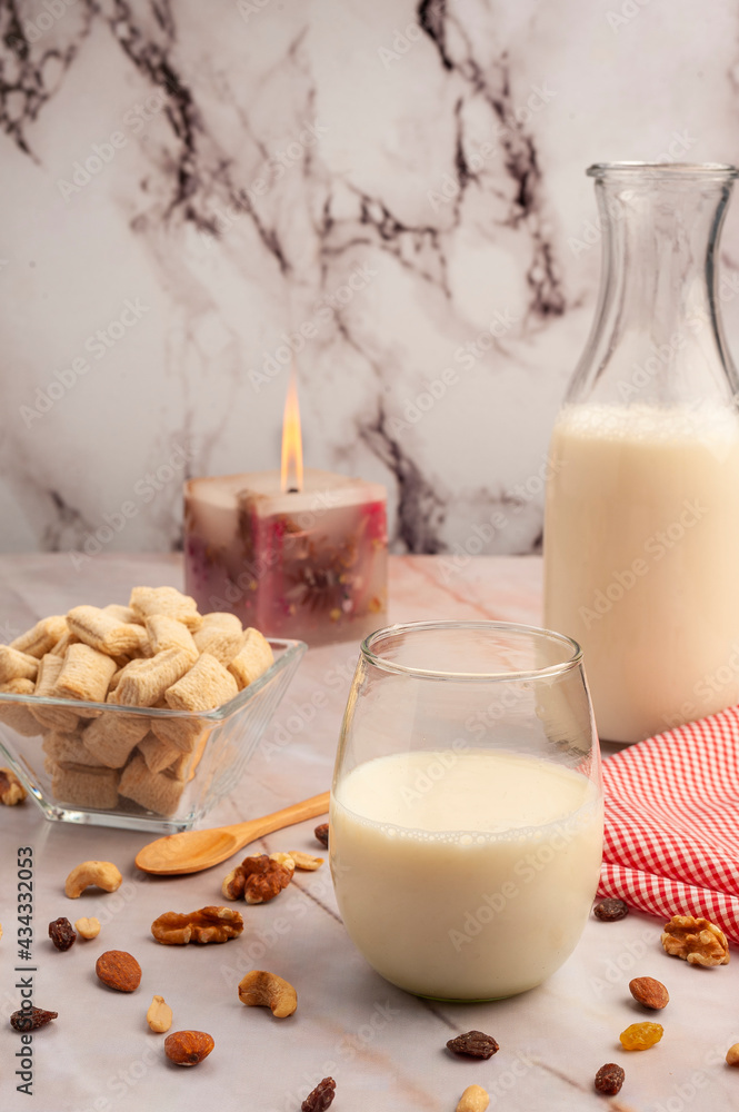 Milk bottle with glass and fiber cereals and nuts, on a marble tabletop and squared napkin, healthy and healthy breakfast and snack. Milk bottle with glass and fiber cereals and nuts, on a marble tabletop and squared napkin, healthy and healthy breakfast and snack.