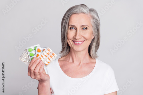 Photo of elderly woman happy positive smile show meds painkillers vitamins health isolated over grey color background