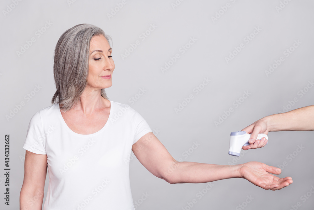 Photo of aged woman look check temperature thermometer protection measure isolated over grey color background Photo of aged woman look check temperature thermometer protection measure isolated over grey color background