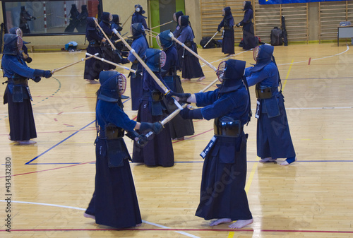 Group of people practising Kendo, a traditional japanese self defense martial art. With samurai robes, bamboo swords and protective masks.