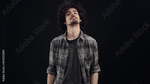 The portrait of a confident young hipster who loves himself who points with both hands towards him and shows the like sign. Isolated on black background, Concept of life. People's emotions. 4k