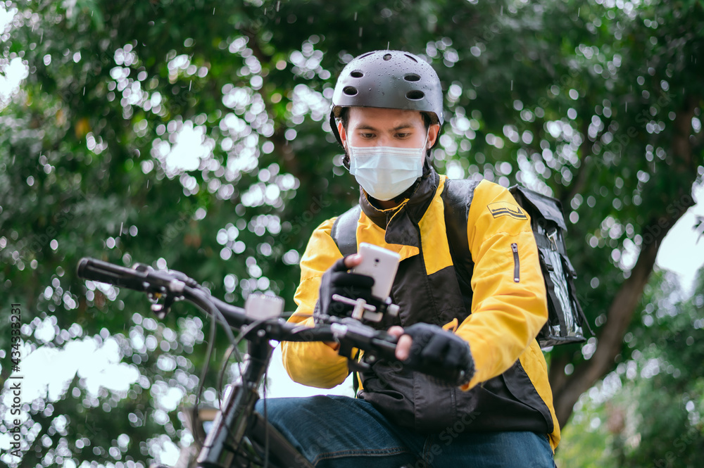 Delivery service staff by bicycle, standing, looking at the phone, showing a map of delivery to customers. Delivery service staff by bicycle, standing, looking at the phone, showing a map of delivery to customers.
