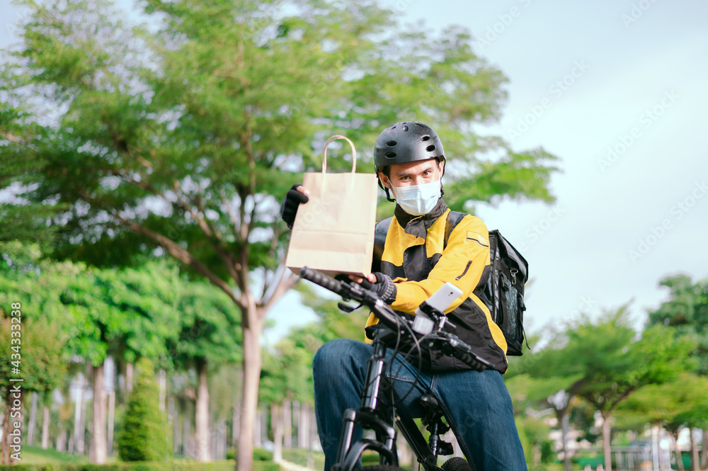 Bike delivery man staff happily staring at the camera while wearing a face mask.