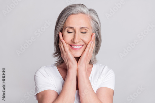 Photo of pretty charming age woman dressed white outfit smiling closed eyes arms cheeks isolated grey color background
