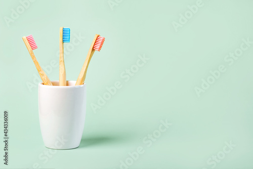 three colored bamboo toothbrushes in a ceramic glass with copy space