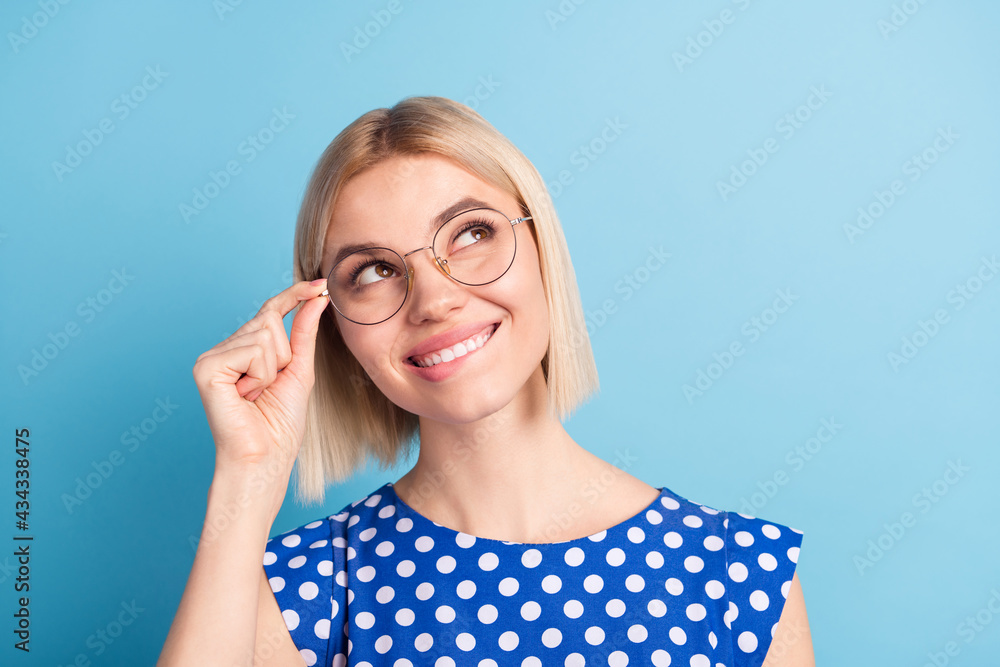 Photo of young attractive girl happy positive smile dream look empty space bite lips isolated over blue color background Photo of young attractive girl happy positive smile dream look empty space bite lips isolated over blue color background