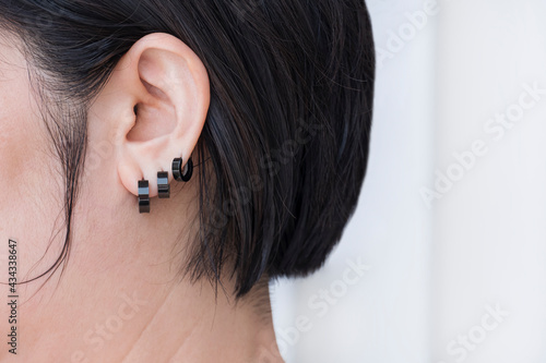 Close up and side view of Bob hair woman wearing 3 black stainless steel earrings on white background