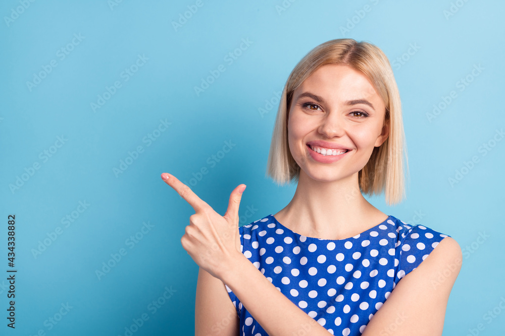 Photo of young attractive girl happy positive smile point finger empty space advert advise choose isolated over blue color background Photo of young attractive girl happy positive smile point finger empty space advert advise choose isolated over blue color background