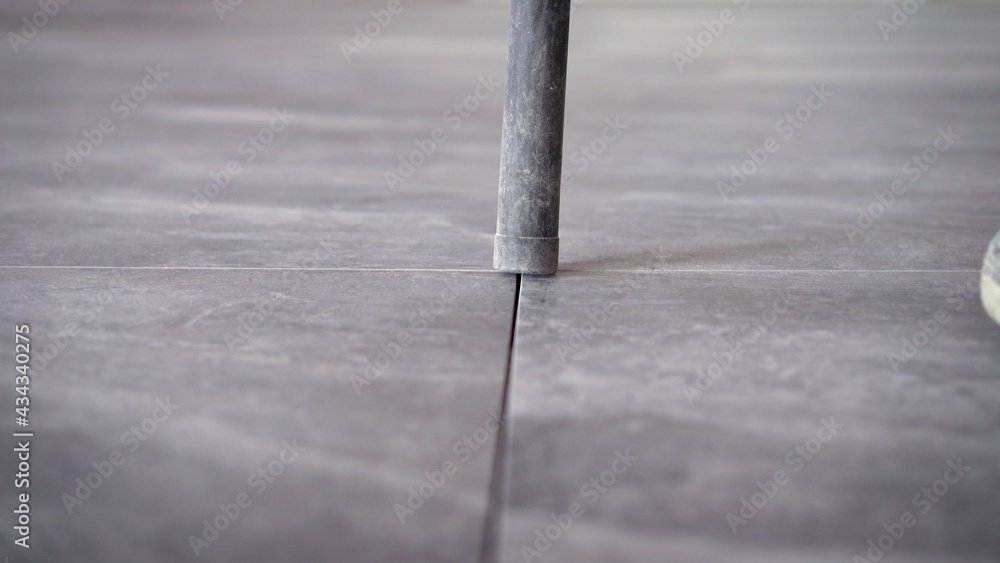 Worker cleans seams between tiles using a vacuum cleaner. Tile master, vacuums the floor to prepare for trowelling. A worker vacuums the ceramic tile floor. Worker cleans seams between tiles using a vacuum cleaner. Tile master, vacuums the floor to prepare for trowelling. A worker vacuums the ceramic tile floor.
