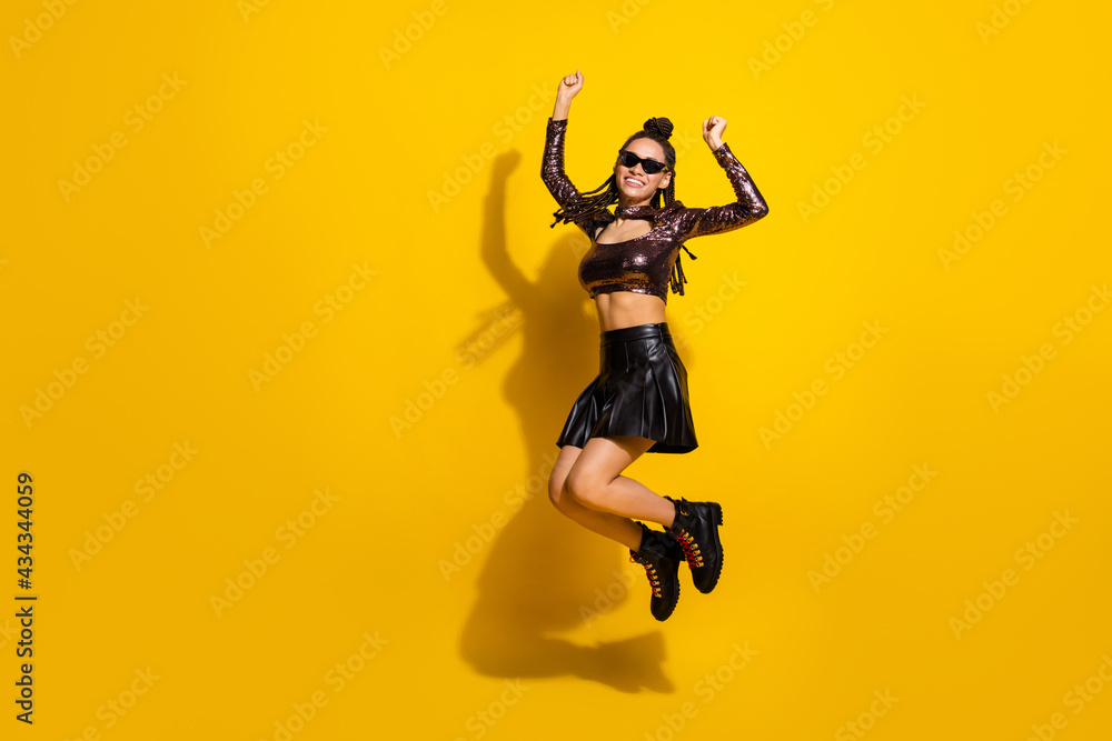 Full length photo of girl jump raise hands wear glasses glossy top short skirt shoes isolated yellow color background