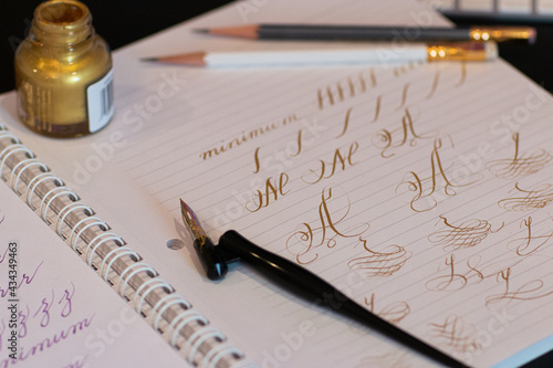 Fotografi Calligraphy practice page, golden ink oblique nib holder and letters with flourishes