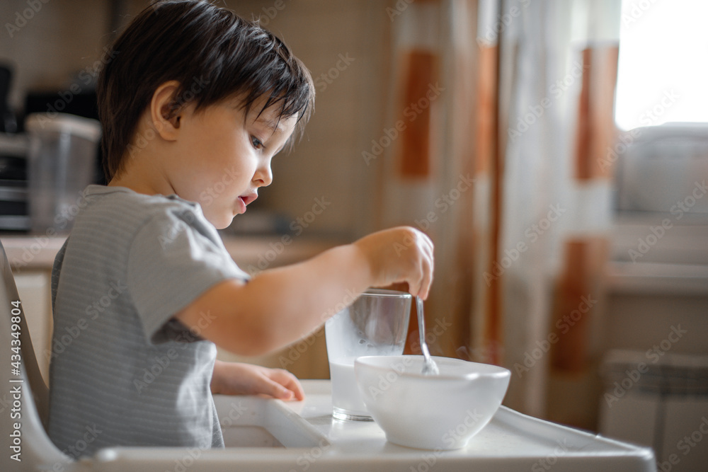 a little boy eats breakfast, eats porridge and drinks milk a little boy eats breakfast, eats porridge and drinks milk