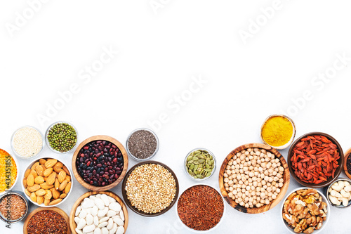 Set of superfoods, legumes, cereals, nuts, seeds in bowls on white background. Superfood as chia, spirulina, beans, goji berries, quinoa, turmeric and other. Copy space, top view