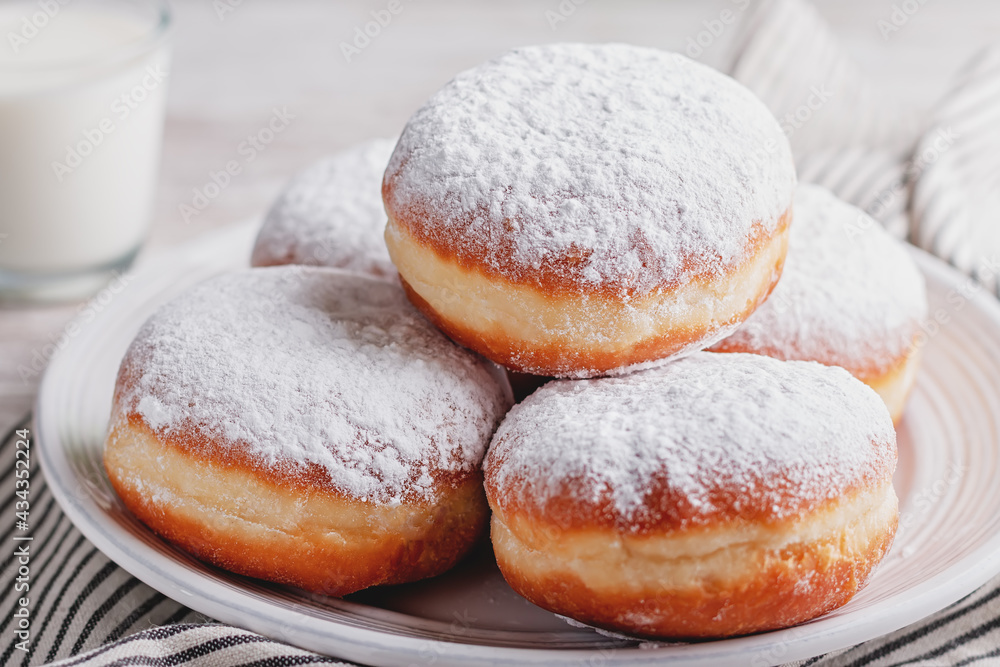 Naklejka premium Delicious strawberry jam filled berliner doughnuts on white plate and glass of milk on wooden table top overhead
