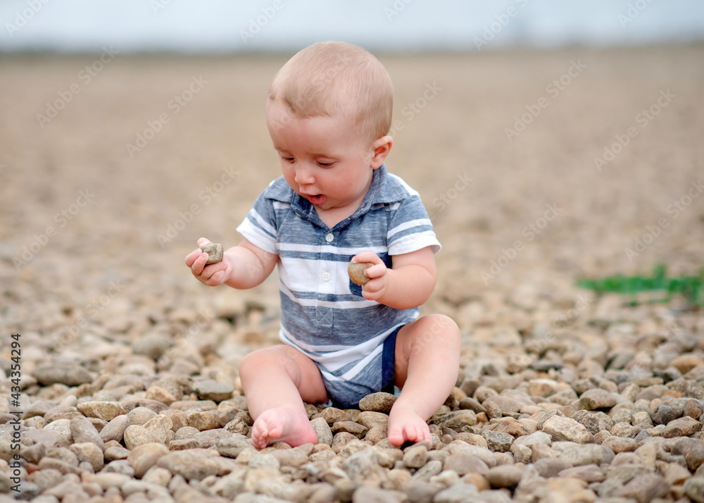 Small boy playing with stones on the seaside Small boy playing with stones on the seaside