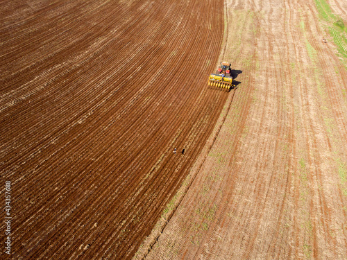 Tractor with seeder in the field. Sowing of corn, Maize in soil, with pneumatic sowing machine during spring season. farmer on tractor with a seeder processes the field.