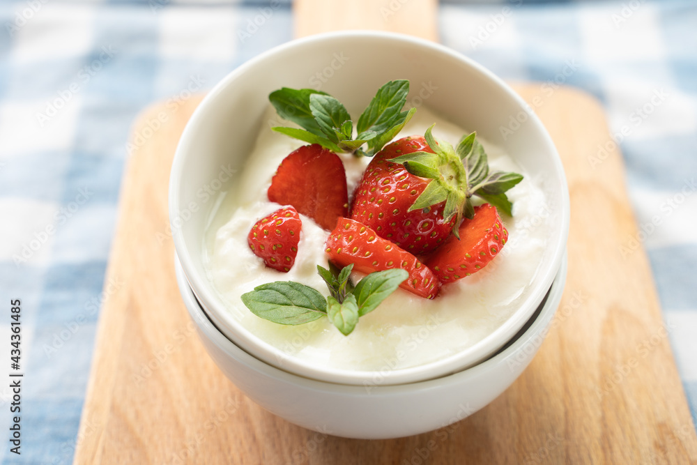 Close-up of yogurt with strawberry on the top in white plates Close-up of yogurt with strawberry on the top in white plates