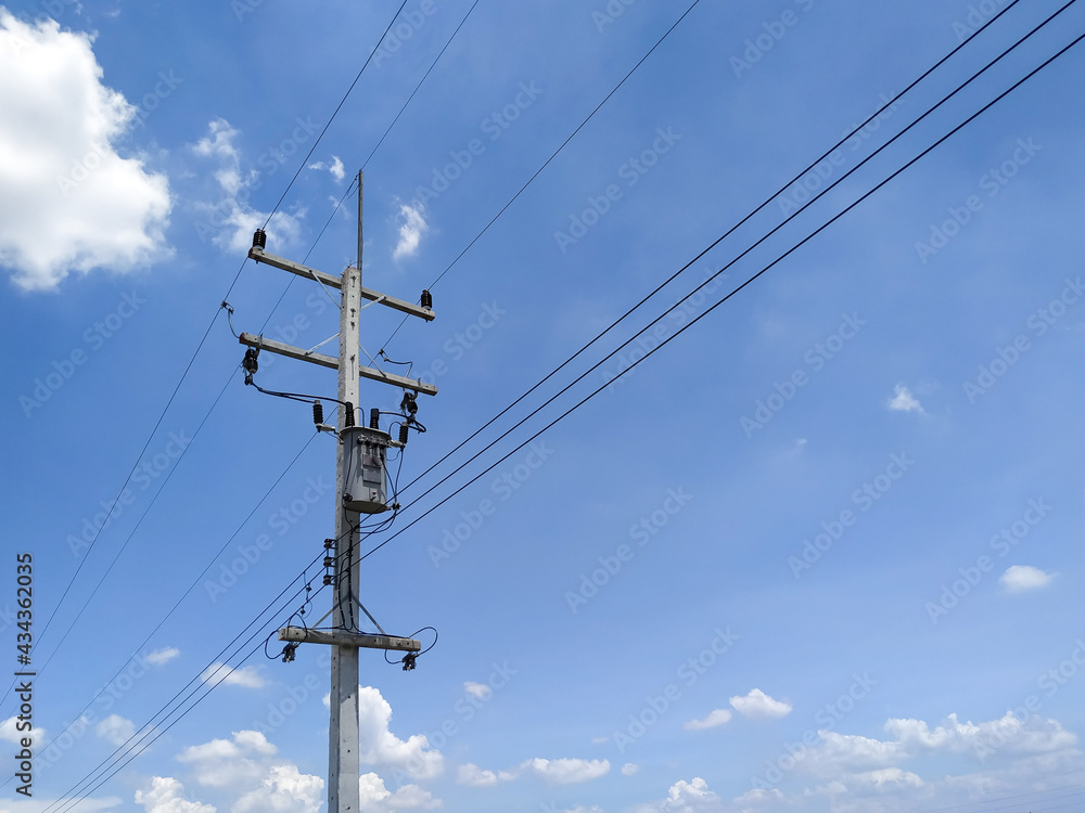 Cement high voltage pole with blue sky and white clouds copy space.
