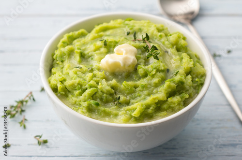 Delicate mashed potatoes with green peas, flavored with butter, spices and thyme on a light blue background. delicious homemade food