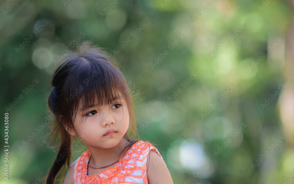 A little adorable Asian girl with sad eyes walking in the park alone. A little adorable Asian girl with sad eyes walking in the park alone.