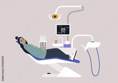 A dentist chair and tools, a monitor with an x-ray image, drills and other instruments in a stomatology cabinet
