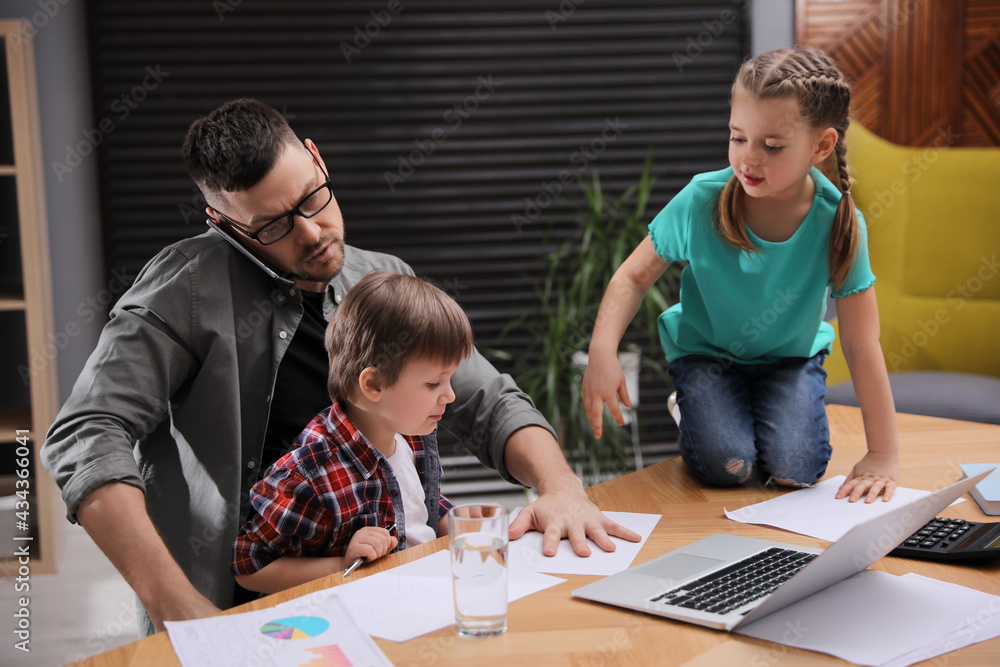 Overwhelmed man combining parenting and work at home Overwhelmed man combining parenting and work at home