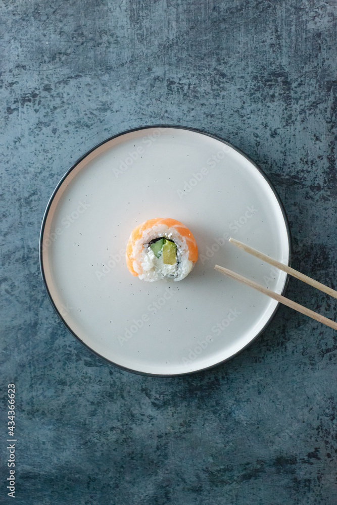 sushi roll Philadelphia on a plate on a pink background. Delicious fresh roll with curd cheese, avocado and salmon sushi roll Philadelphia on a plate on a pink background. Delicious fresh roll with curd cheese, avocado and salmon