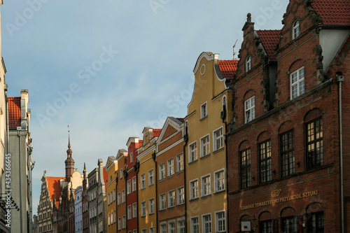 A close up of the facades of tall building in the middle of Old Town in Gdansk, Poland. The buildings have many bright colors, they are richly decorated. City tour. Clear day.