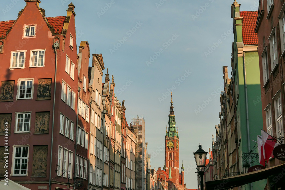 A close up of the facades of tall building in the middle of Old Town in Gdansk, Poland. The buildings have many bright colors, they are richly decorated. High tower of Town Hall. City tour. Clear day.