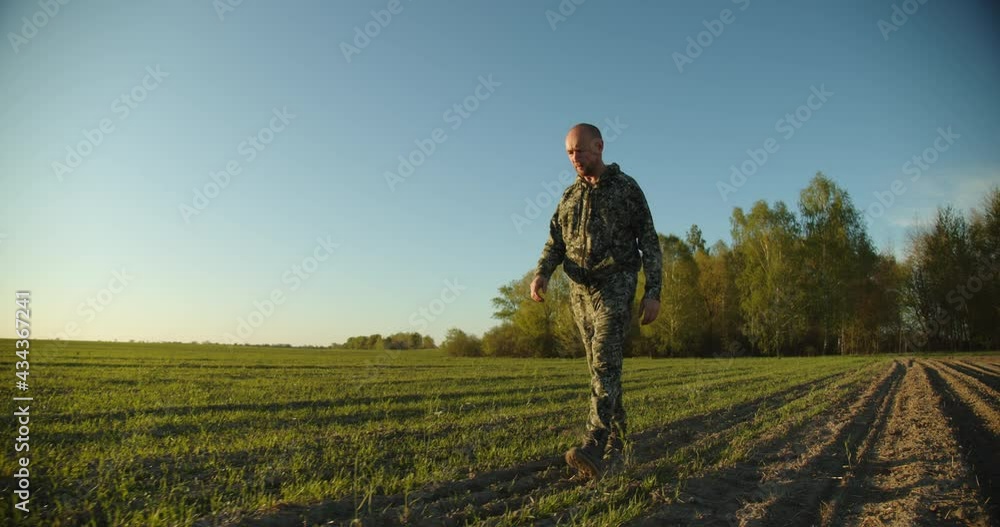Farmer walks through a young green field during sunset. Adult man farmer walking and checks his agriculture field. Human walking on agriculture field. SLow motion. 4K footage. Farmer walks through a young green field during sunset. Adult man farmer walking and checks his agriculture field. Human walking on agriculture field. SLow motion. 4K footage.