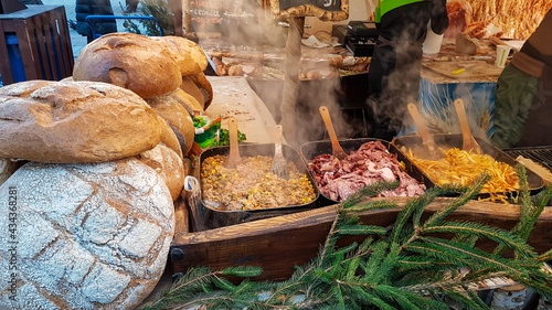 A wooden stand filled with home baked bread and Polish cuisine specialities, like fried sausage, fried onions and minced meat. The food is very hot and there is steam coming outof it.