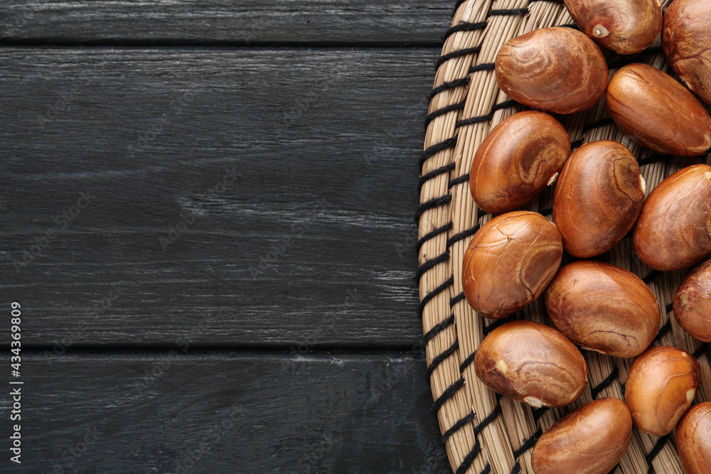 Obraz premium Raw jackfruit seeds on black wooden table, flat lay. Space for text