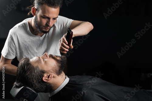 Trimming the beard with a shaving machine. Advertising for barbershop and men's beauty salon