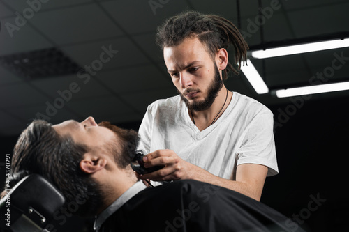 Trimming the beard with a shaving machine. Advertising for barbershop and men's beauty salon