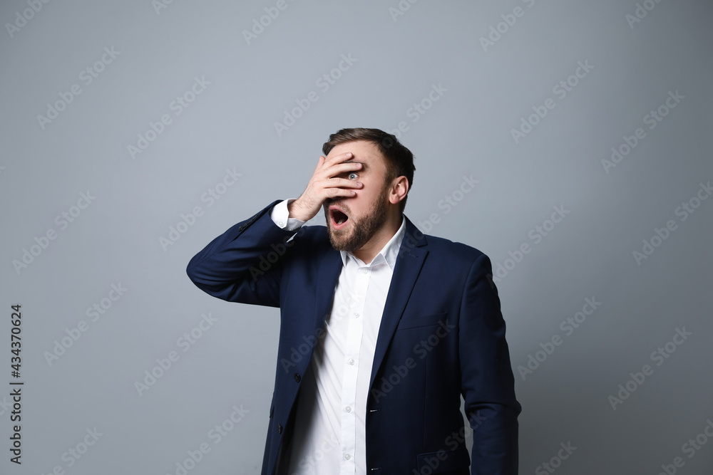 Young businessman feeling fear on grey background Young businessman feeling fear on grey background