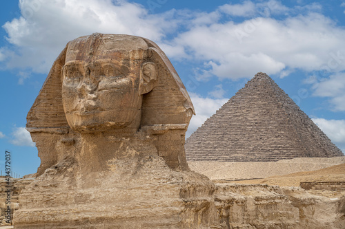 The front face and body of the Sphinx and the biggest Great Pyramid of Khafre appear side by side in the desert of Giza  Cairo  Egypt. Horizontal Copy Space