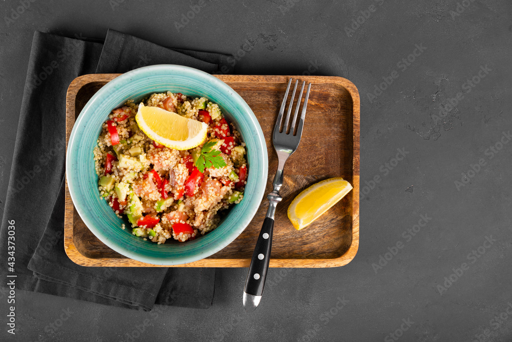 Salmon salad with tomatoes, avocado and quinoa in a blue bowl on a dark gray background top view, a dish of balanced diet Salmon salad with tomatoes, avocado and quinoa in a blue bowl on a dark gray background top view, a dish of balanced diet