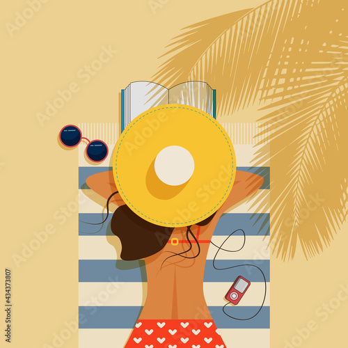 Beautiful girl lies on the beach. A girl in a red swimsuit and a yellow hat is reading a book. Tropical trees. Glasses, a pink player, a book on a blue-striped towel