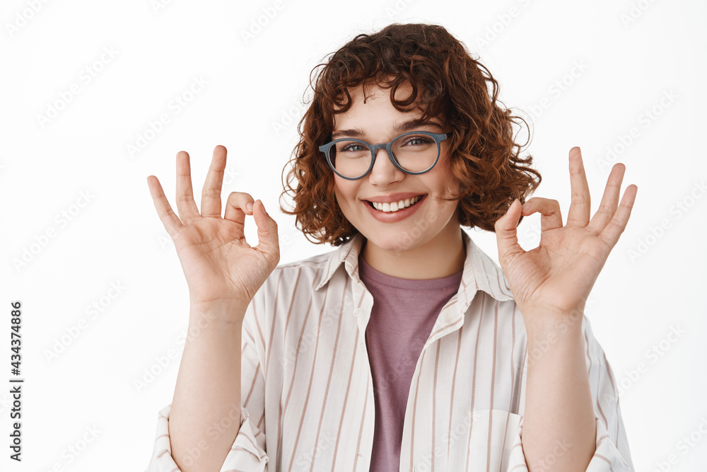 Smiling cute queer girl in glasses showing okay ok gesture, looking assured and confident in her choice, guarantee and recommend advertisement, like and approve something good Smiling cute queer girl in glasses showing okay ok gesture, looking assured and confident in her choice, guarantee and recommend advertisement, like and approve something good