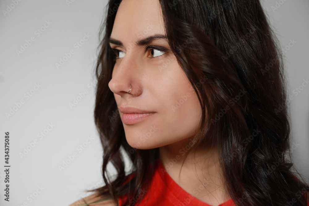 Young woman with nose piercing on grey background, closeup Young woman with nose piercing on grey background, closeup